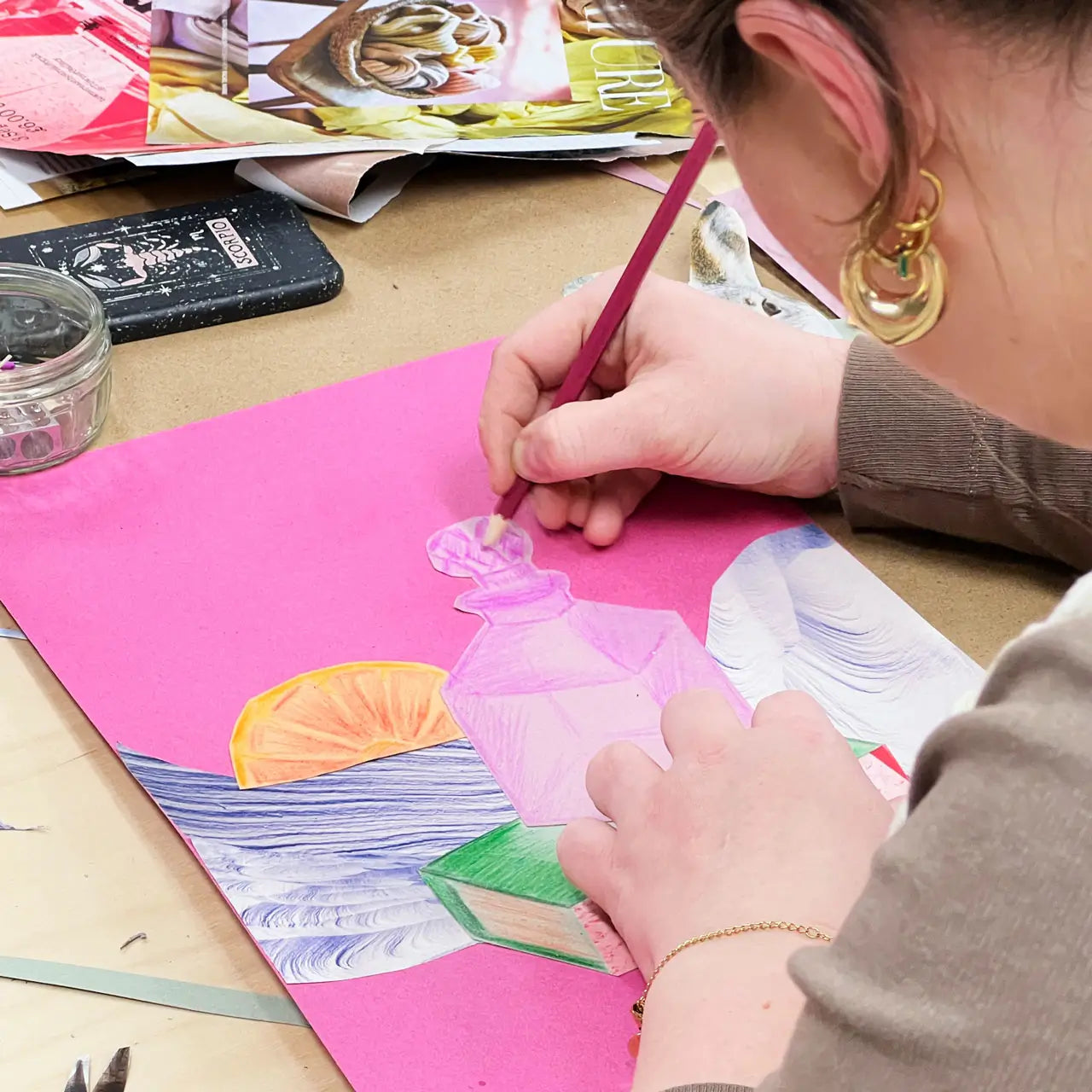 Person coloring a picture of a dress on pink paper with a pink crayon.